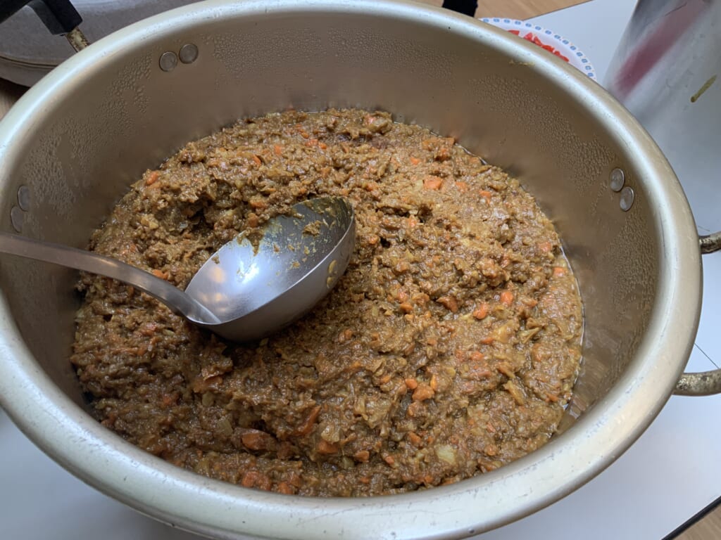 大きな鍋に入った挽肉料理を調理中。介護施設の食事準備風景。